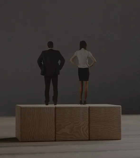 Miniature man and woman standing on the wooden blocks. The concept of the equal opportunities for genders.